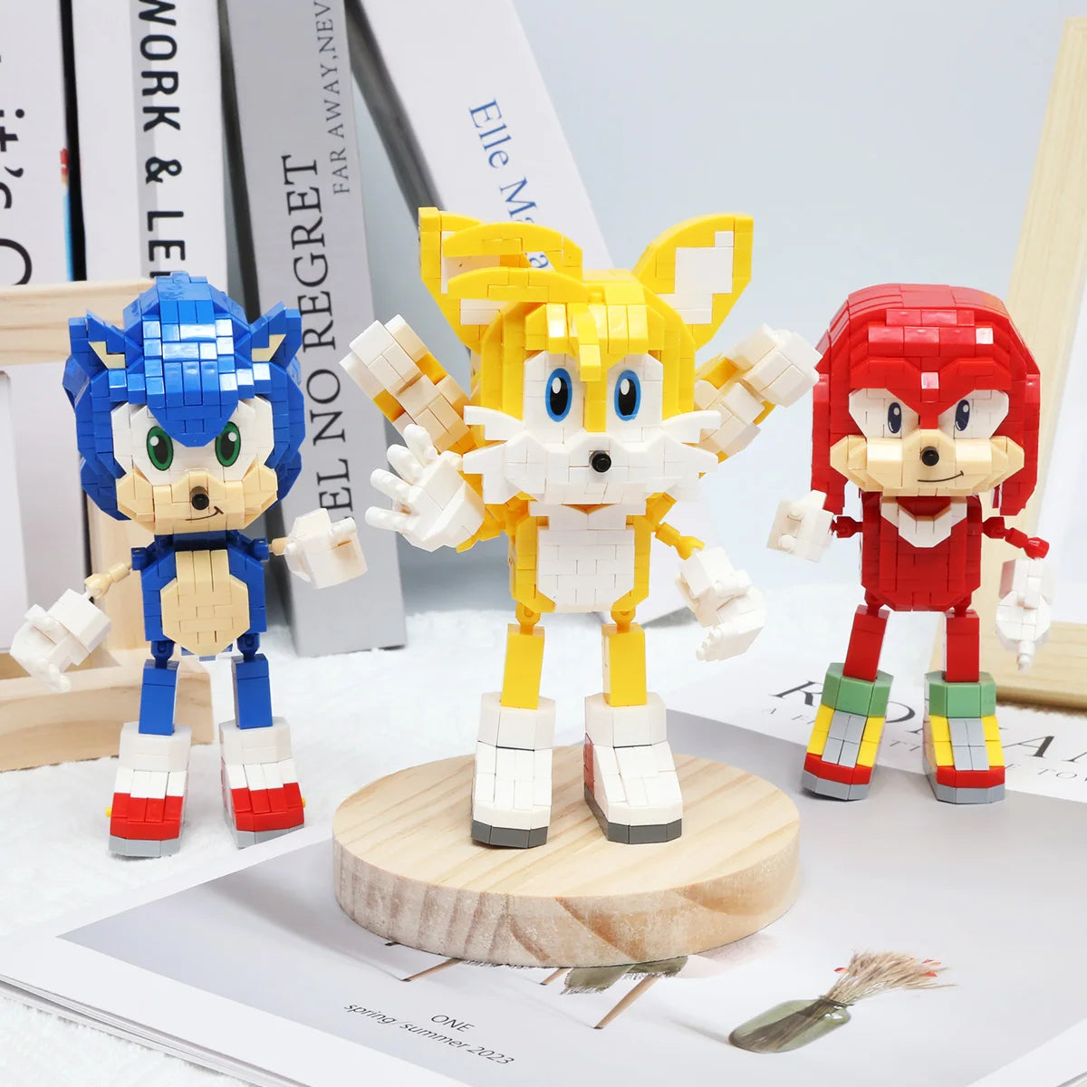 A set of three Kawaii dinosaur building block figures in blue, yellow, and red standing on a wooden base.