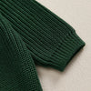 A close-up of a dark green knit sweater with textured stitch pattern.
