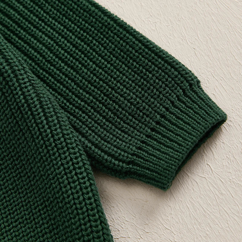 A close-up of a dark green knit sweater with textured stitch pattern.