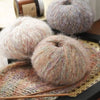 A close-up of colorful mohair yarn balls and a knitted item displayed on a wooden surface.