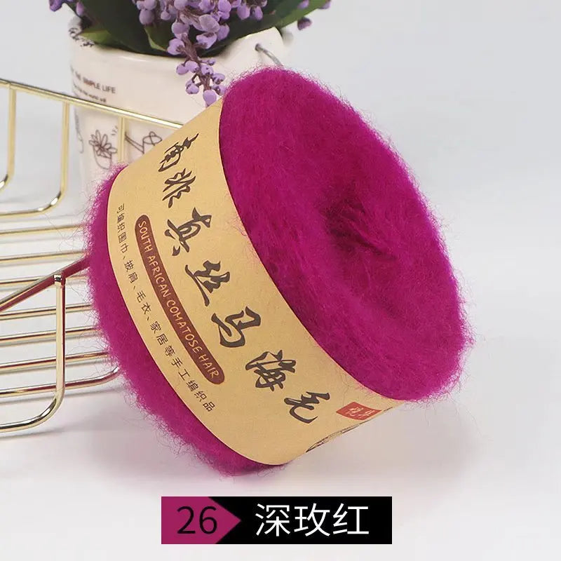 A vibrant magenta silk mohair blended yarn is displayed next to a gold wire rack.