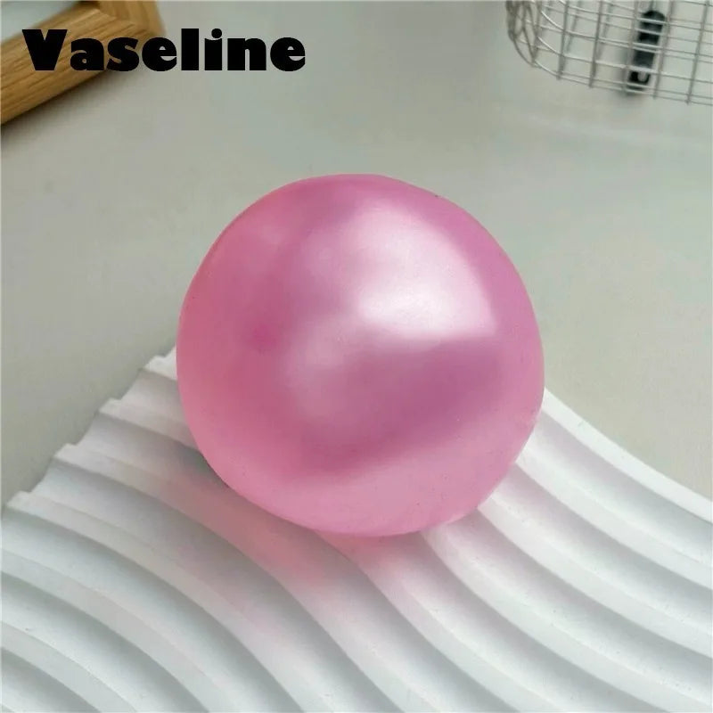 A smooth, pink silicone fidget ball resting on a white, wavy surface.