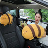 A woman in a car is holding two yellow plush animal pillows, one resembling a bee and another like a frog.