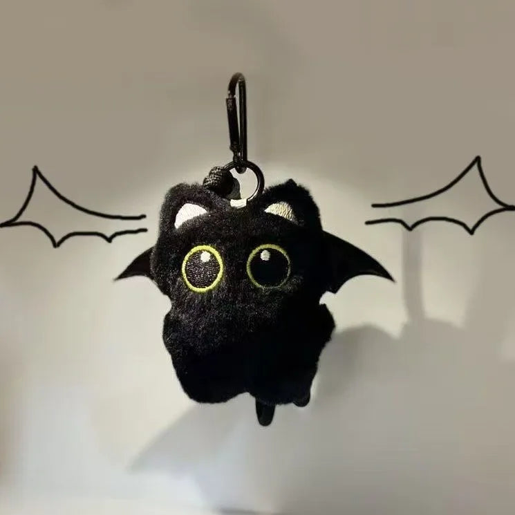 A black plush cat keychain charm with large yellow eyes is hanging against a light background.