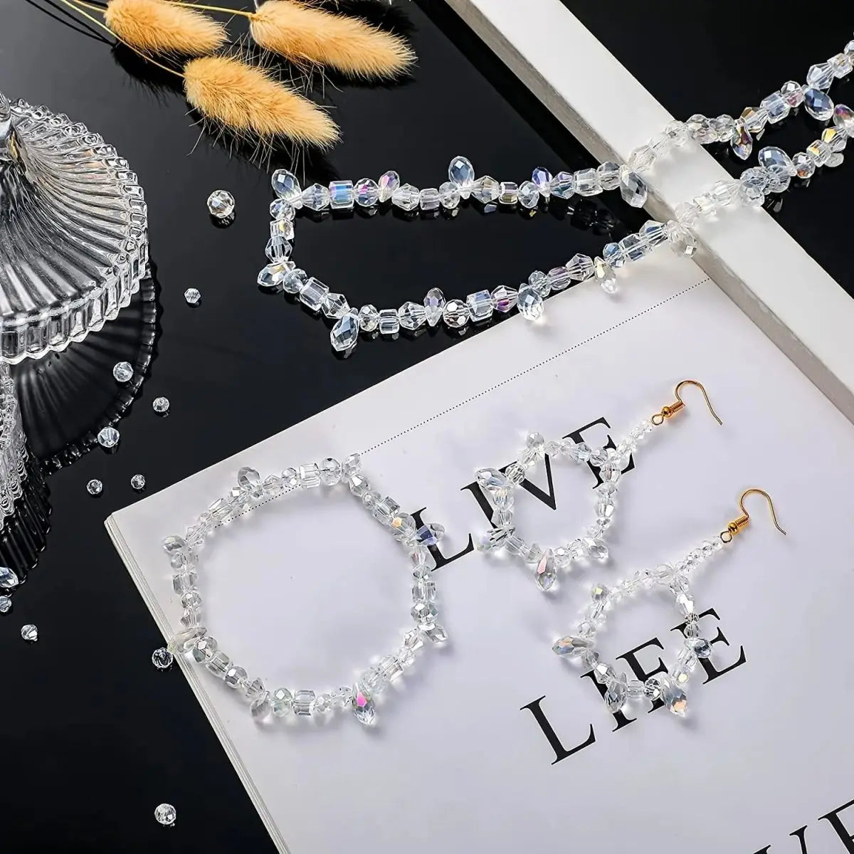 A collection of clear crystal glass beads and stringing material with an AB finish displayed on a white background.