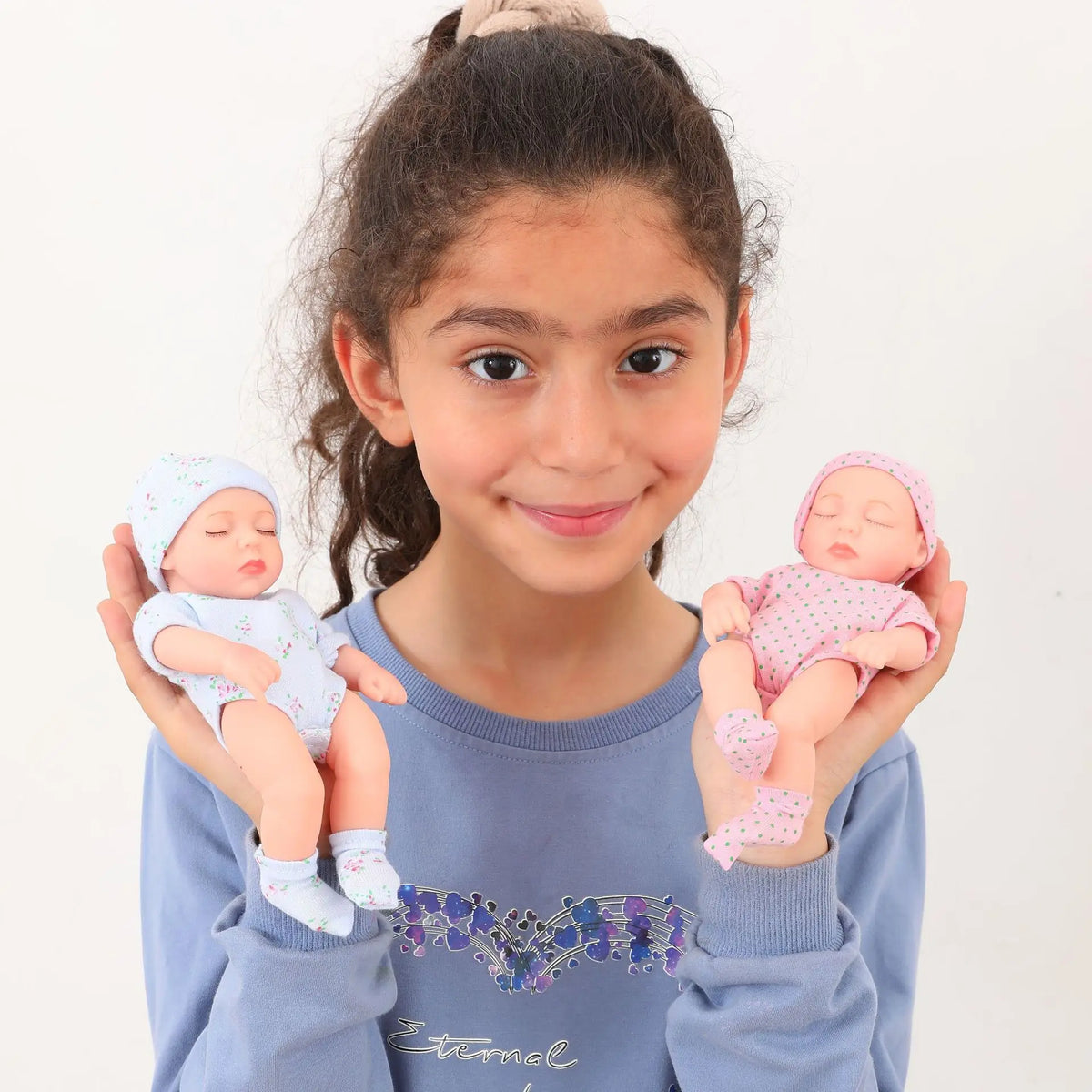 A girl holds a realistic soft vinyl baby doll with a newborn outfit set.