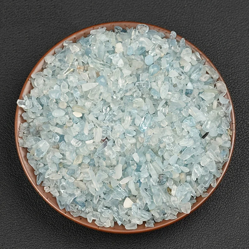 A pile of light blue to translucent aquamarine chips in a shallow brown dish.