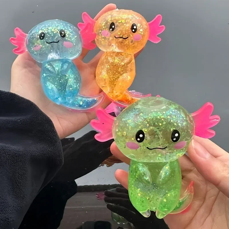 A hand holds three squishy axolotl stress relief toys in shades of blue, orange, and green.