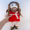 A plush doll representing Jesus with long brown hair and a beard wearing a red robe.