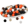 A white oval dish filled with various round silicone beads in shades of black, white, brown, and orange.