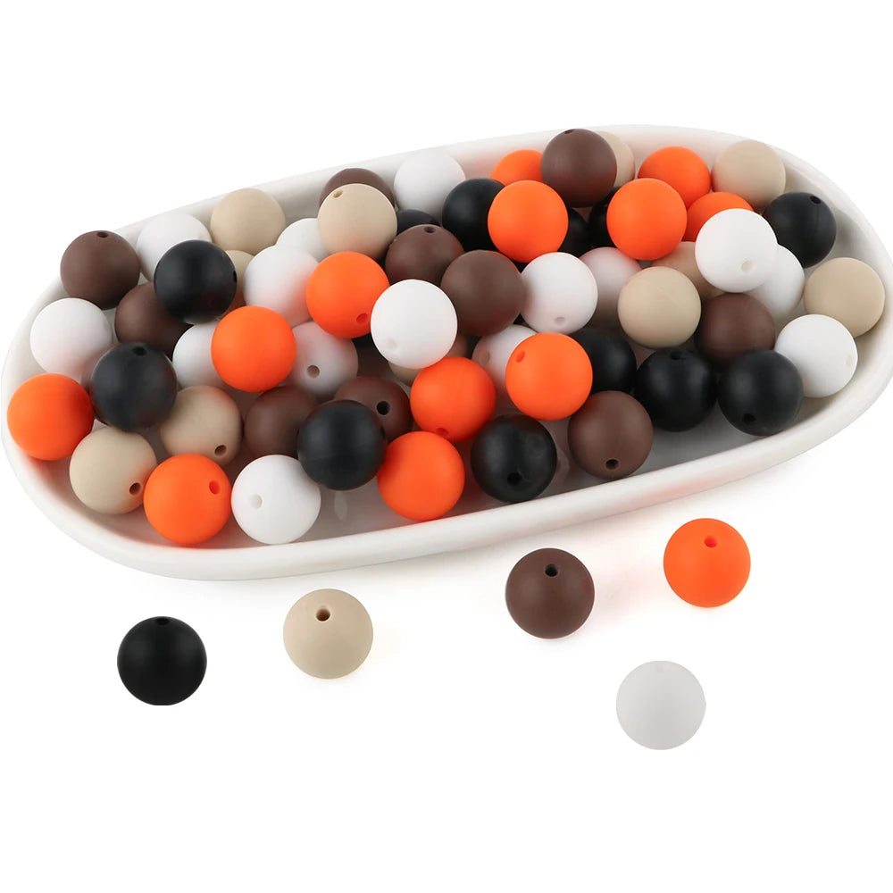 A white oval dish filled with various round silicone beads in shades of black, white, brown, and orange.