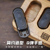 A black push slider fidget toy is shown resting in a wooden box, demonstrating its smooth texture and design.