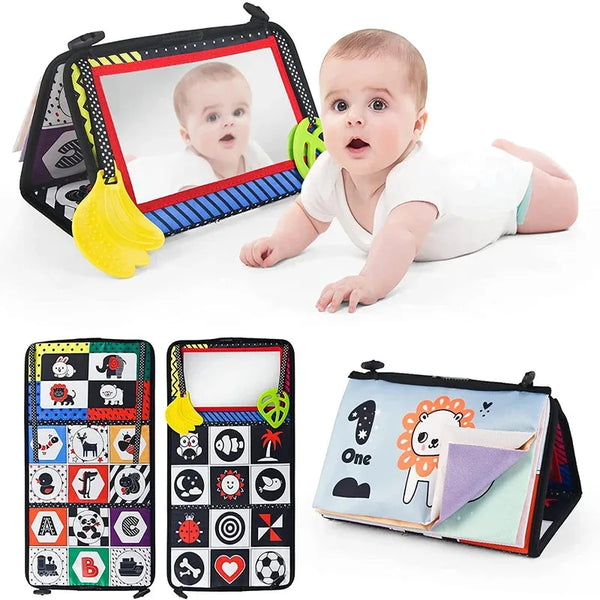 A baby is looking into a Montessori cloth book with a distorting mirror, featuring various images and shapes.
