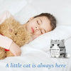 A handmade crochet cat figurine with a smiling face resting on white bedding.