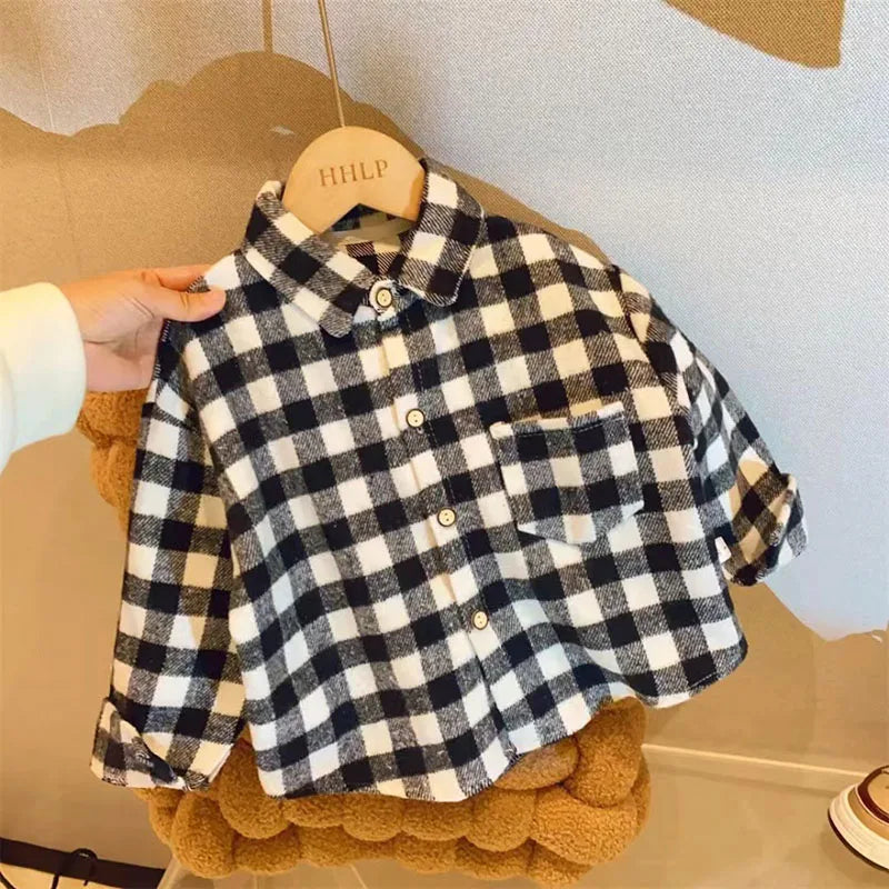 A plaid button-up shirt with a black and white pattern is displayed on a hanger against a light background.