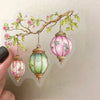 Pink and green floral lanterns hanging from a branch on clear adhesive sheet