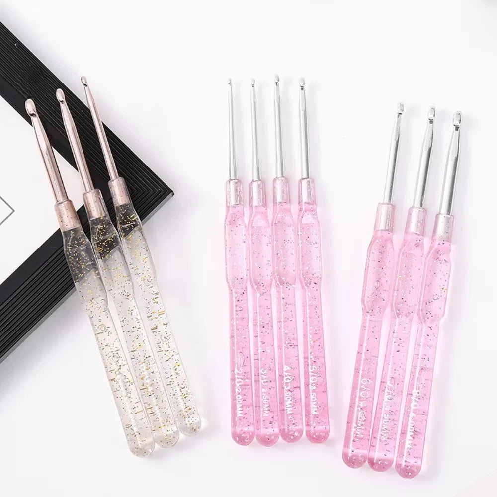A set of seven aluminum crochet hooks with color-coded pink handles displayed on a white background.