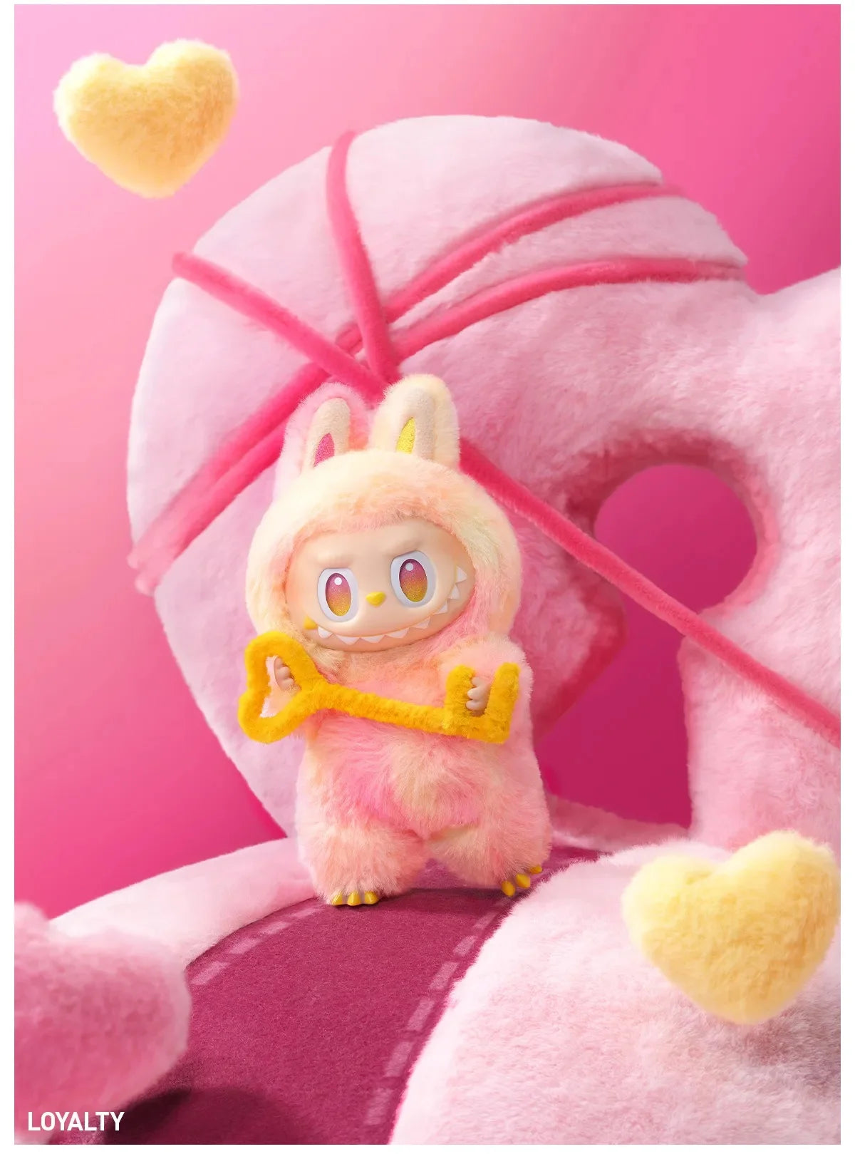 A pink Labubu vinyl plush pendant blind box with yellow accents and a heart shape.