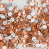 A close-up of various flatback glass crystal rhinestones in shades of peach and silver.