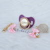A personalized crystal pacifier with a clip featuring the name Lina and a matching pink ribbon and pearl accents.