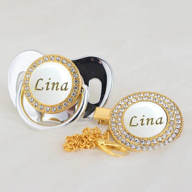 A gold and white bling pacifier clip featuring the name Lina on a circular charm.