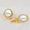 Gold and white bling pacifier clip with the name Lina engraved on a circular pendant