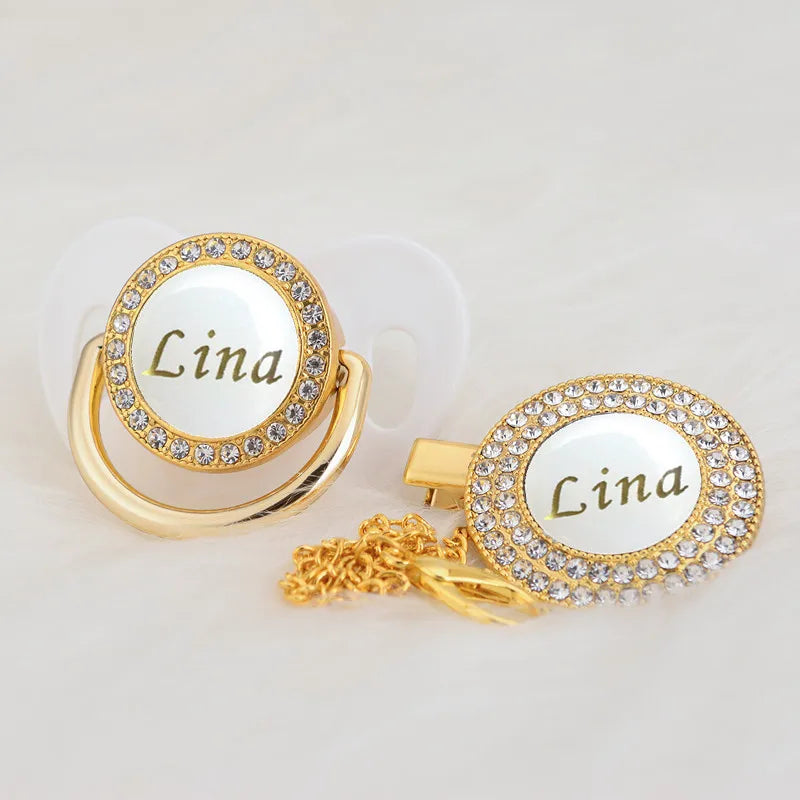 Gold and white bling pacifier clip with the name Lina engraved on a circular pendant