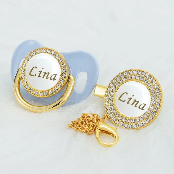 Gold and white bling pacifier clip with a circular name plate featuring the name Lina