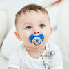 A baby is shown holding a blue evil eye pacifier and clip set.