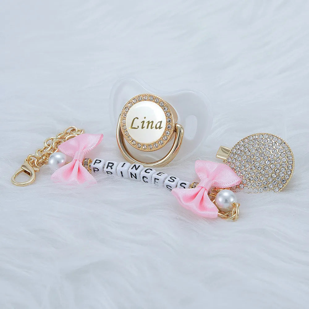 A personalized crystal pacifier featuring the name Lina, set with gold accents and a matching clip.
