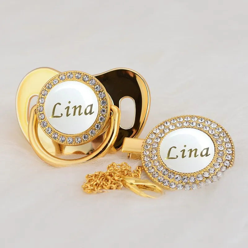 Gold and white bling pacifier clip featuring the name Lina