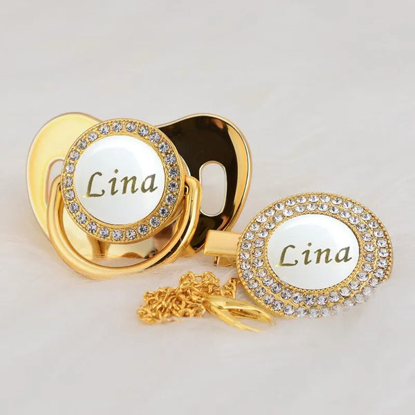 Gold and white bling pacifier clip featuring the name Lina