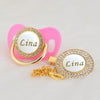 Gold and white bling pacifier clip with a pink silicone holder and a gold charm featuring the name Lina