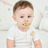 A baby is shown holding a personalized crystal pacifier and clip gift set.