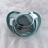 A clear silicone pacifier with a rounded top and surrounding ring, resting on white fur.