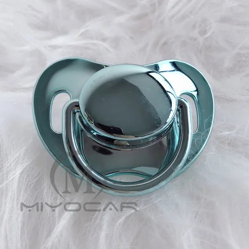 A clear silicone pacifier with a rounded top and surrounding ring, resting on white fluffy material.
