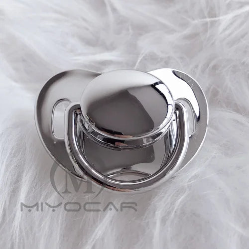 Silver silicone pacifier with a rounded top resting on white fluffy fur