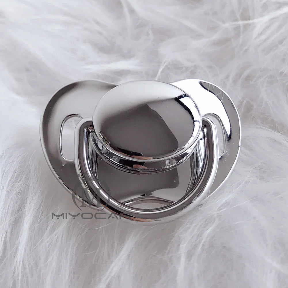 Silver silicone pacifier with a rounded top resting on white fluffy fur