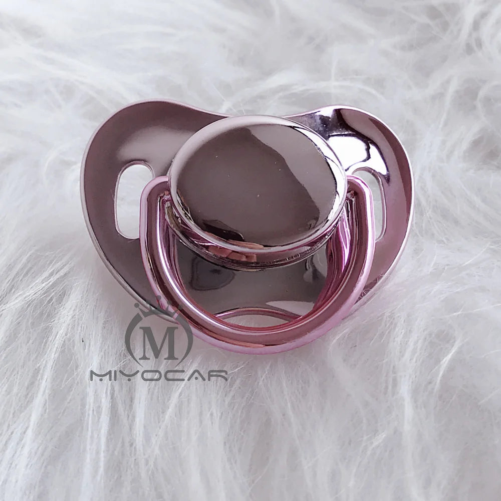 A pink silicone pacifier with a smooth dome and surrounding clip, resting on white fluffy material.