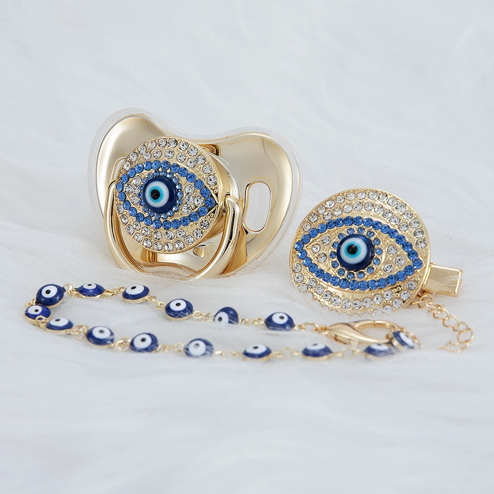 Gold jewelry set featuring an evil eye pacifier and clip with blue and silver stones