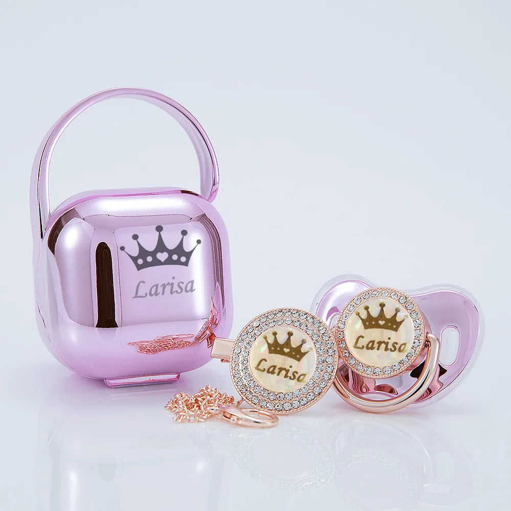 A pink rose gold bling pacifier and clip gift set with a crown design.