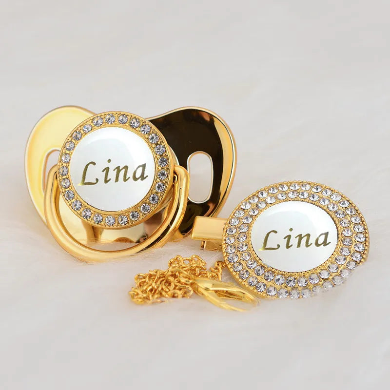 Gold and white bling pacifier clip featuring the name Lina on a circular charm