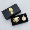 A black box containing a personalized crystal pacifier and matching clip with gold accents.