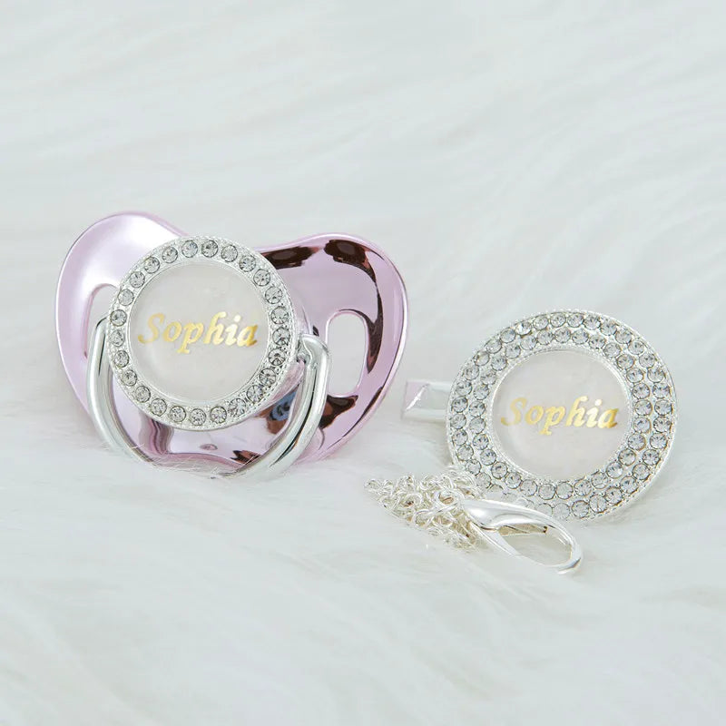 A pink rhinestone pacifier and clip set featuring the name Sophia on a clear disc.